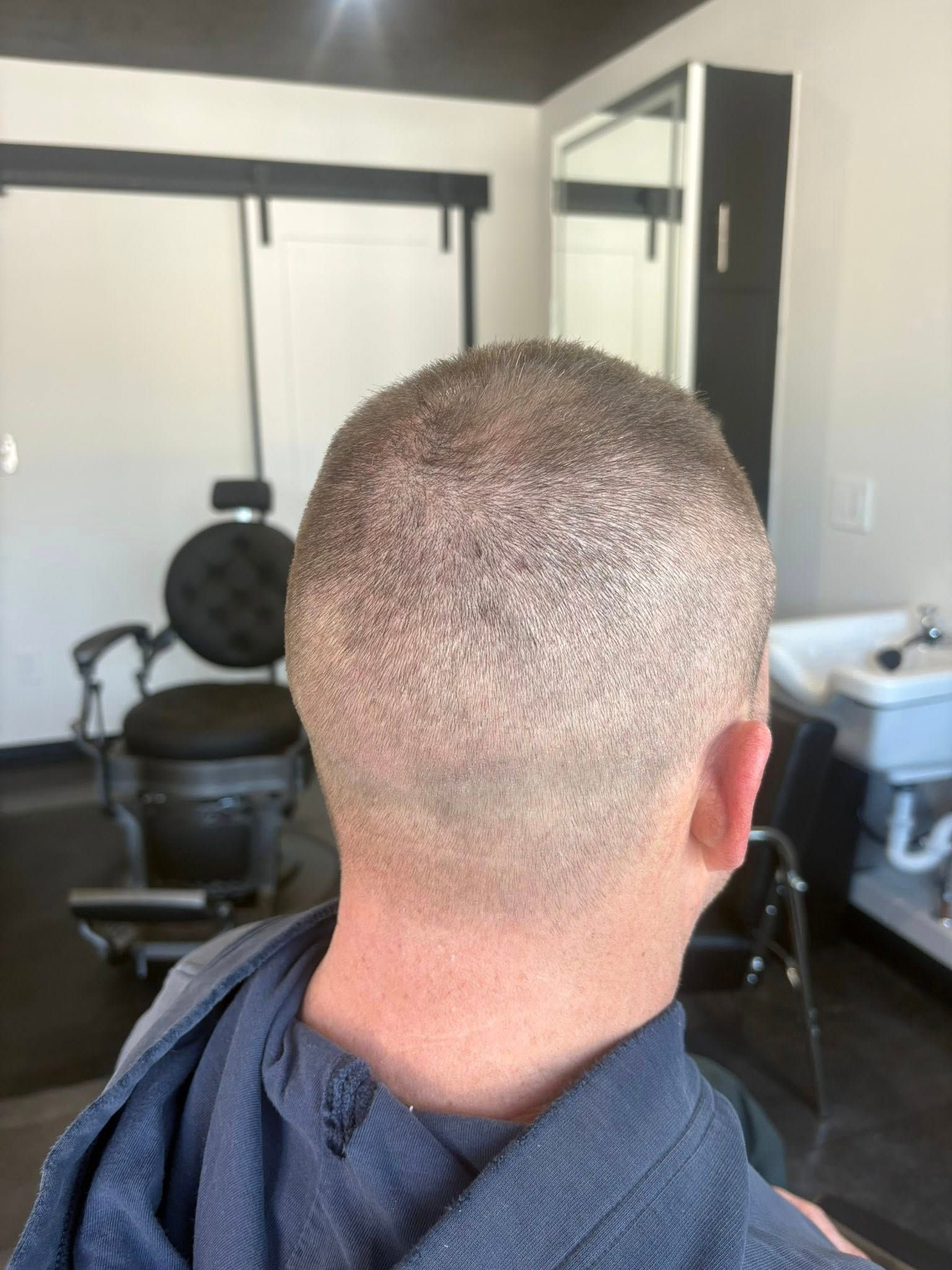 Back view of a person with a close-cut haircut in a barber shop.
