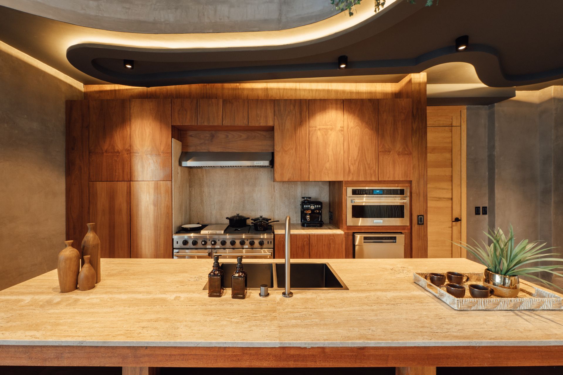 Wooden kitchen with island, stove, and built-in oven. Neutral color scheme.