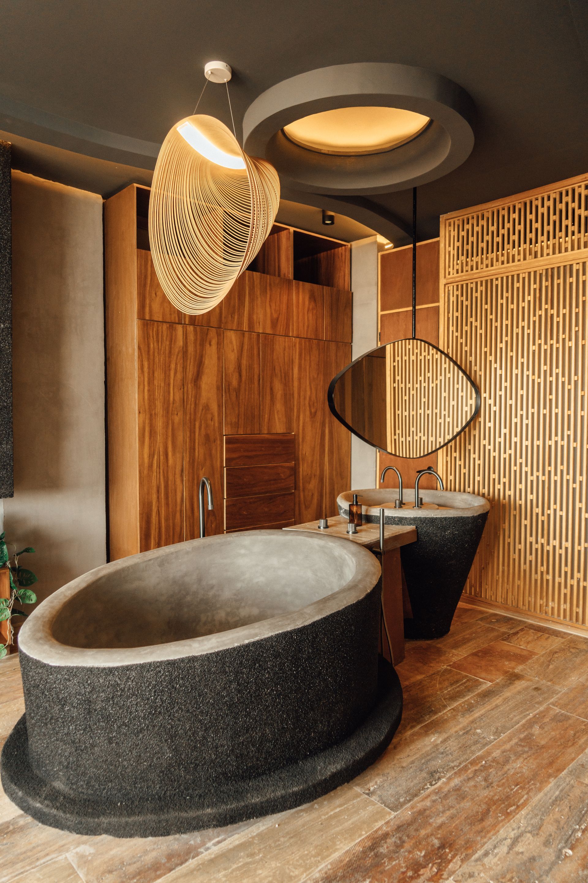 A luxury bathroom with a stone bathtub, sink, and a decorative light fixture.