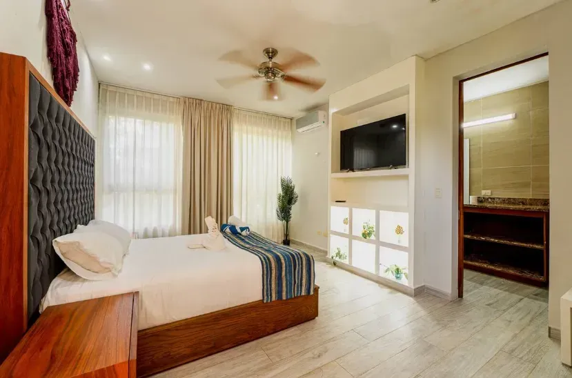 A hotel room with a king size bed , television , and ceiling fan.
