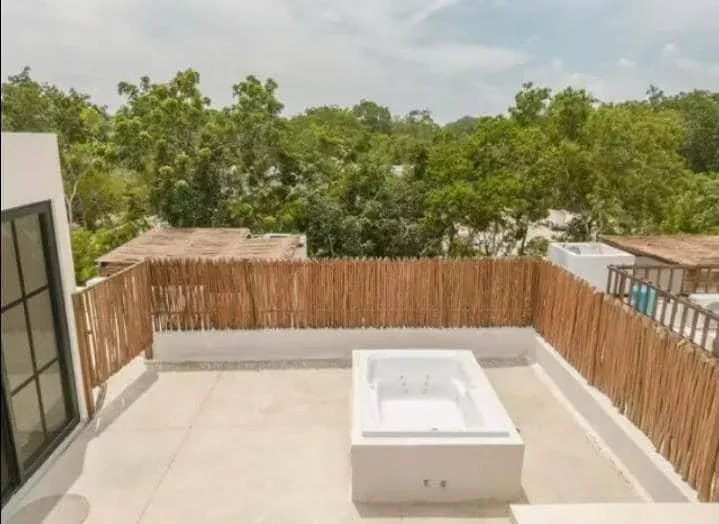 A rooftop with a bathtub and trees in the background
