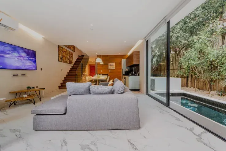 A living room with a couch , television , and a swimming pool.