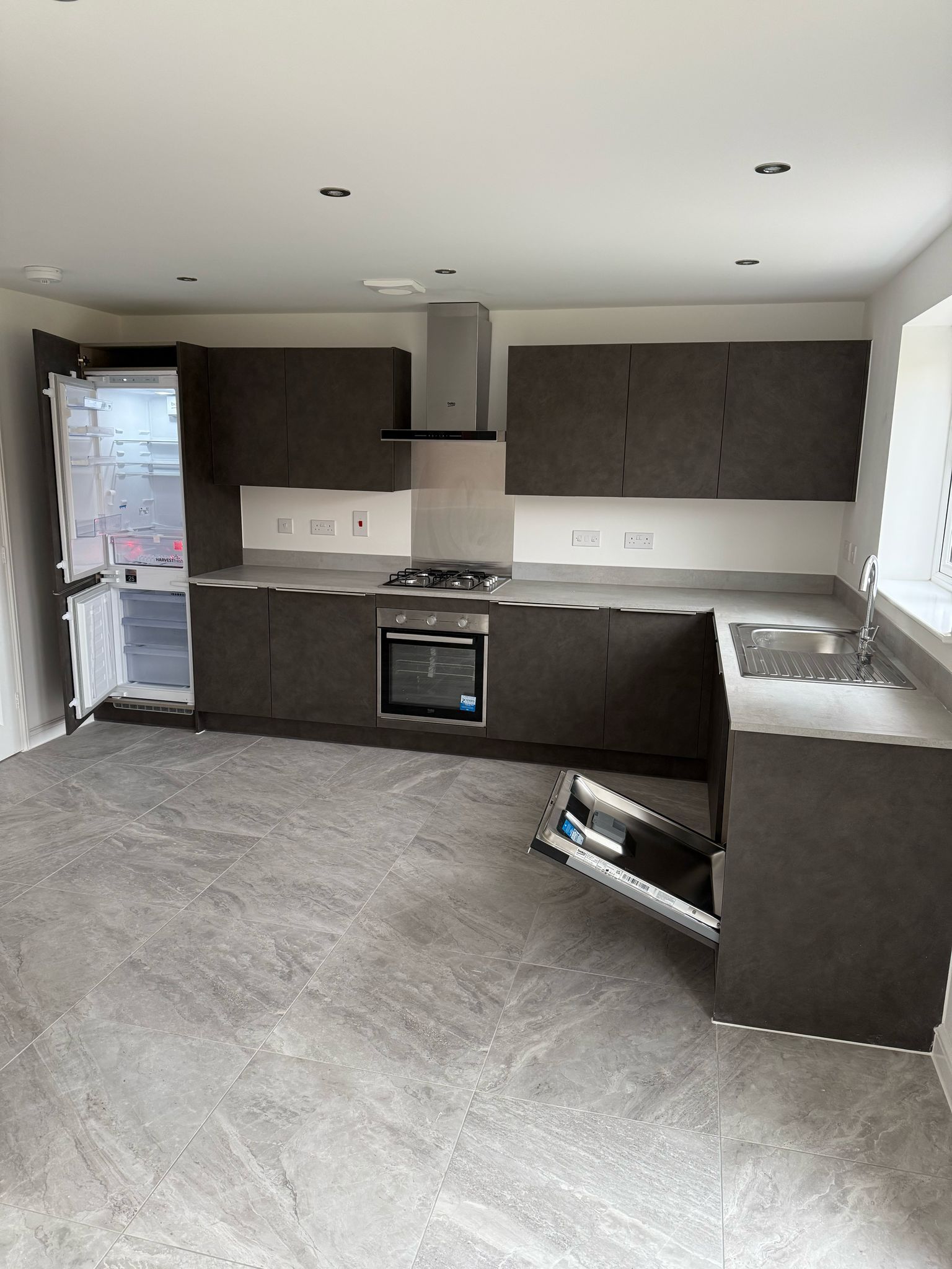 Modern kitchen with gray cabinets, countertop, and appliances. Open refrigerator door.