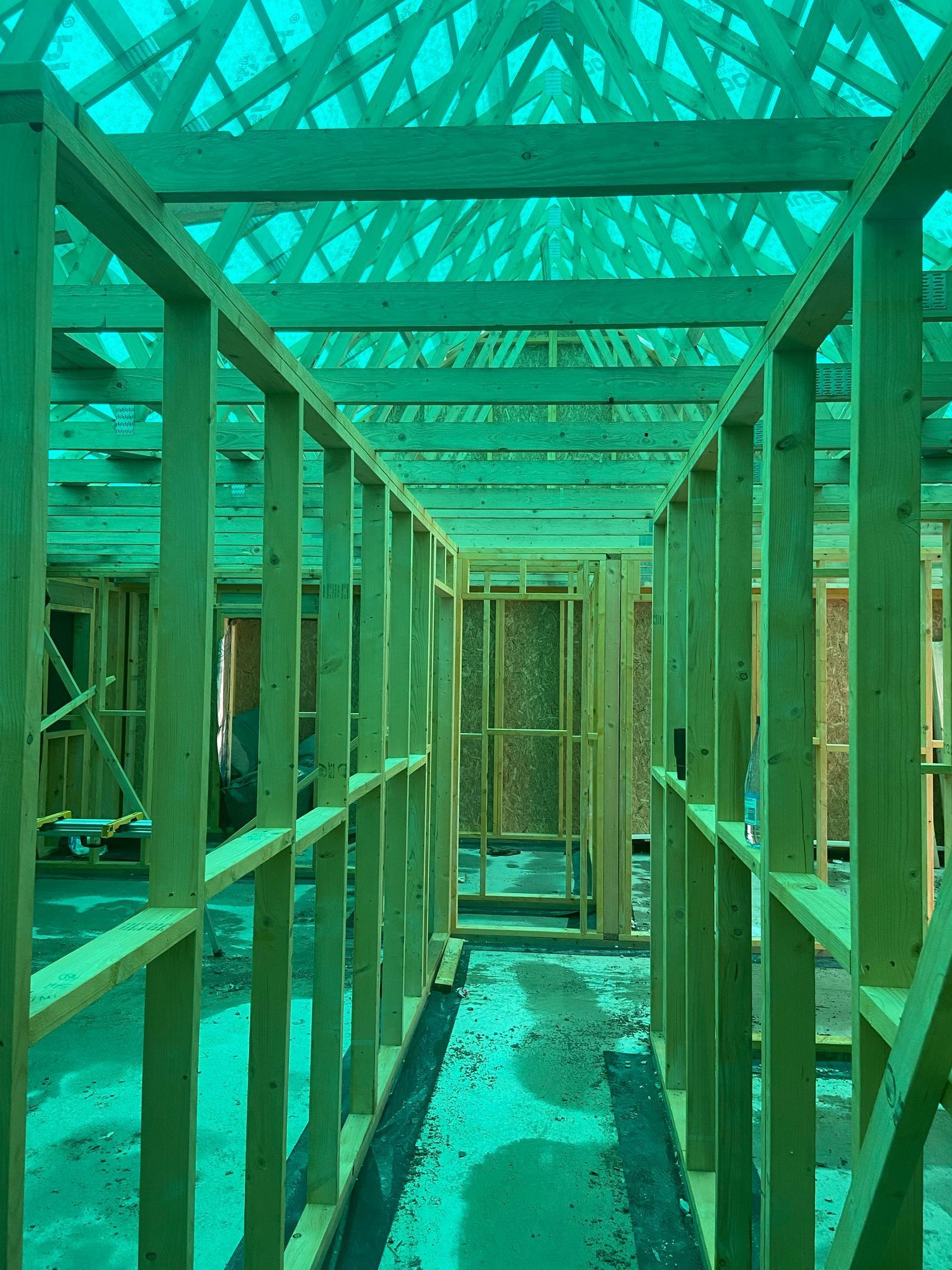 Interior view of a building under construction, showing wooden frames and a green translucent roof.