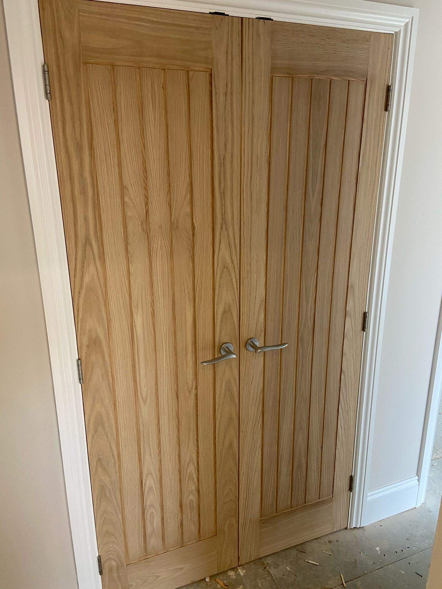 Double wooden doors with vertical grooves, silver handles, and white trim.
