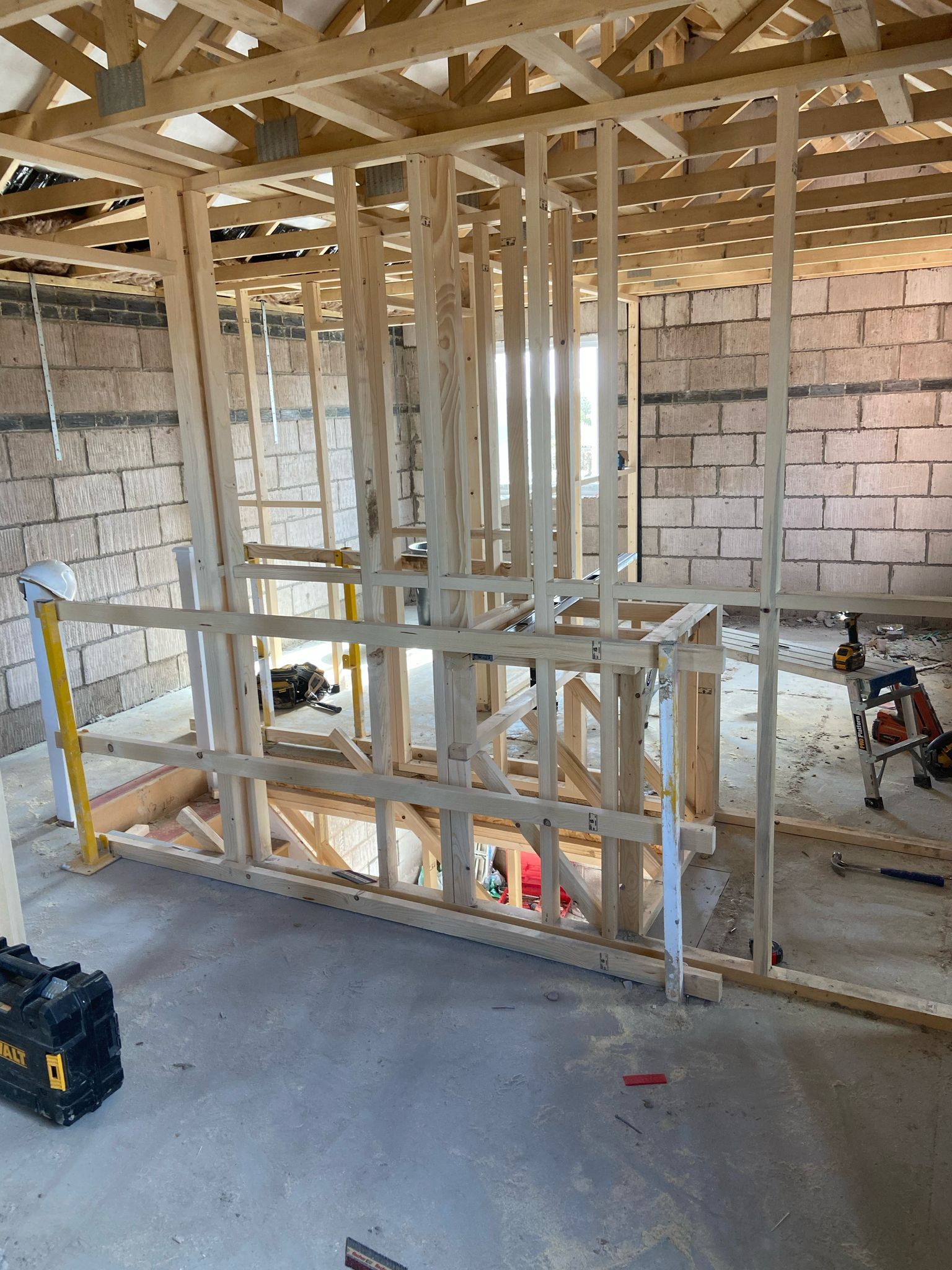 Interior construction: wooden framework for a wall, plumbing, unfinished brick walls, tools.