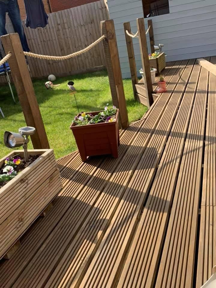 Wooden deck with rope railing, planters, and a grassy backyard.