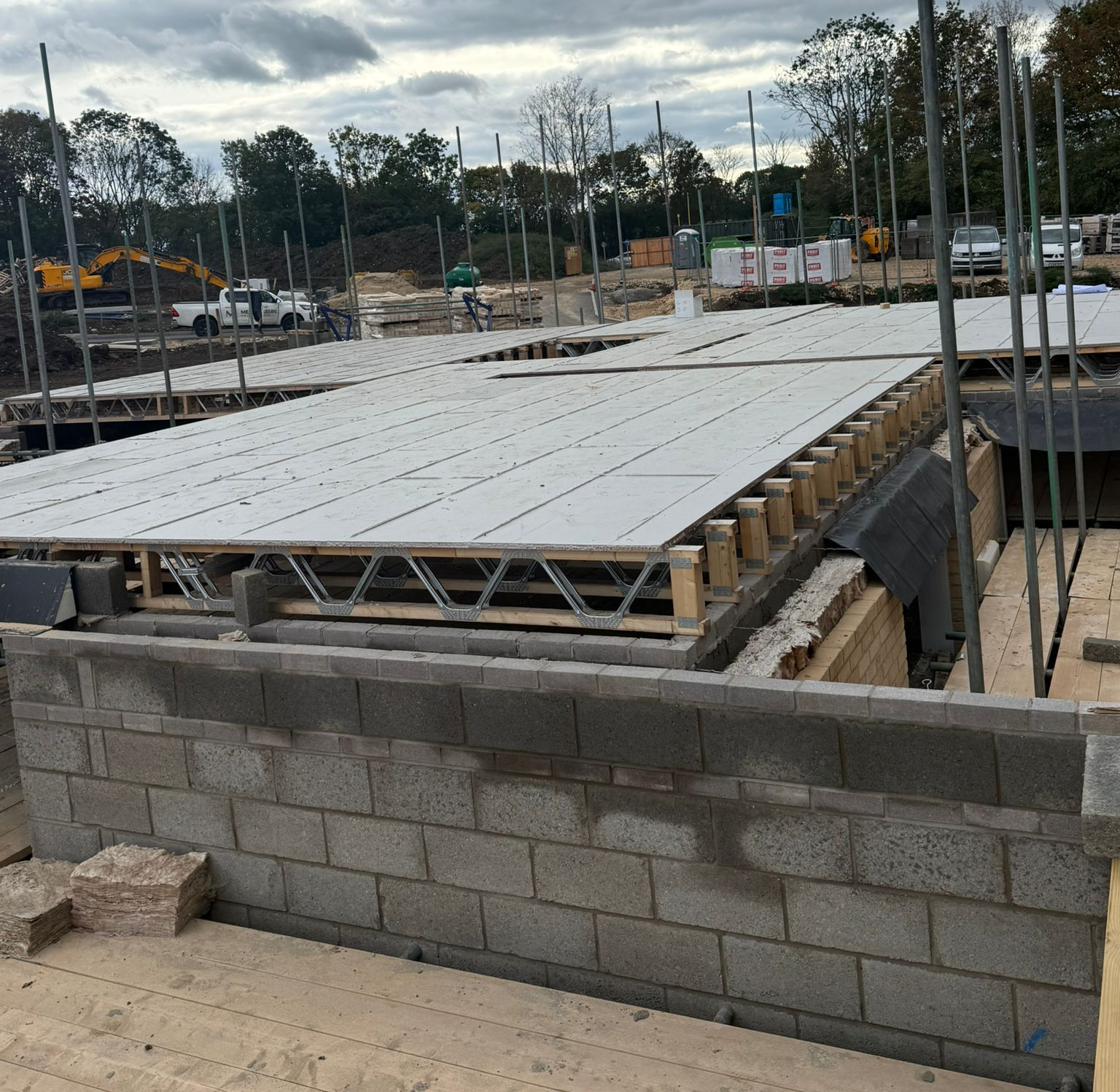 Construction site with concrete block walls, floor joists, and white floor panels.