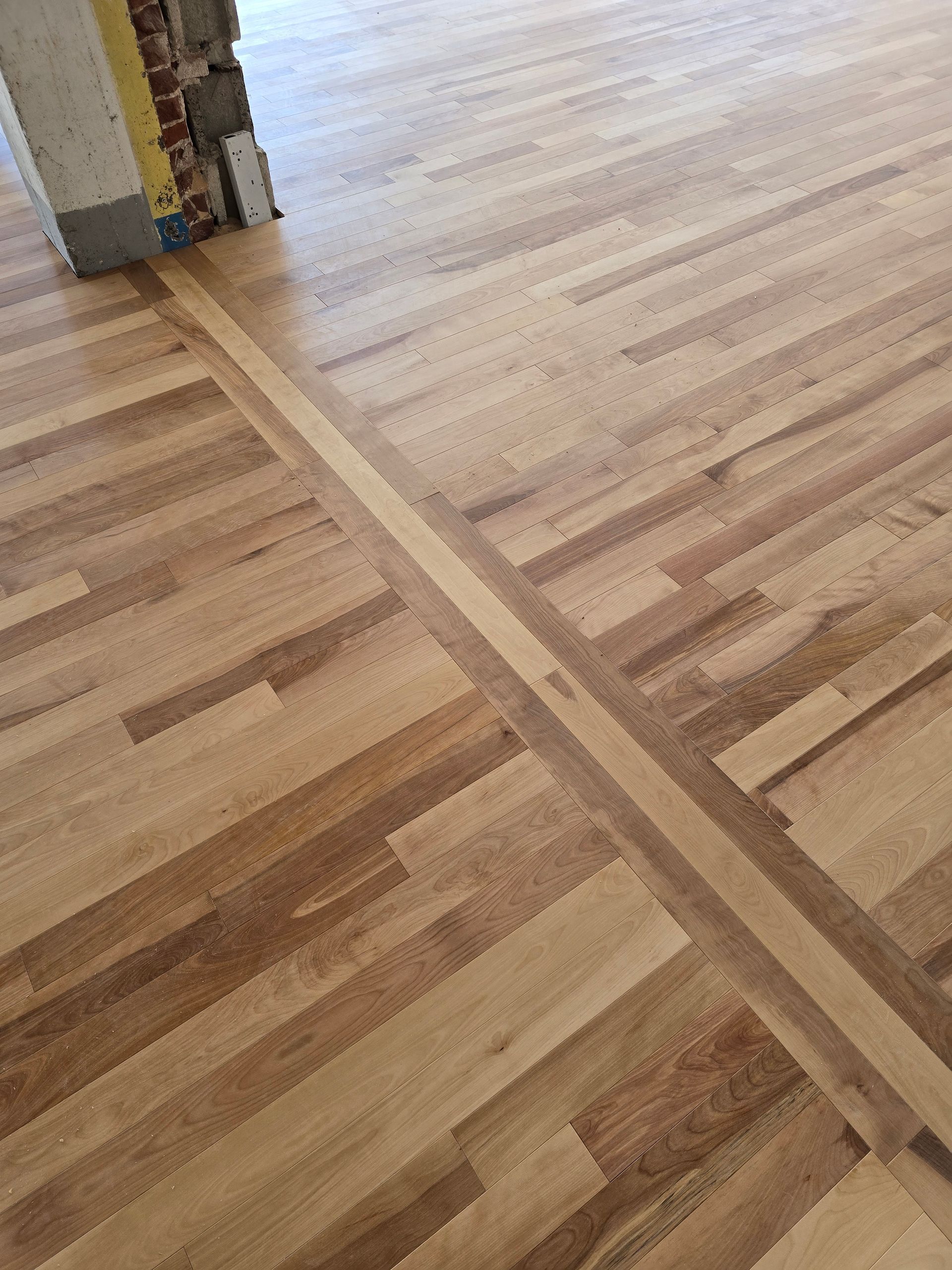 Un gros plan d'un plancher en bois avec un mur de briques en arrière-plan.