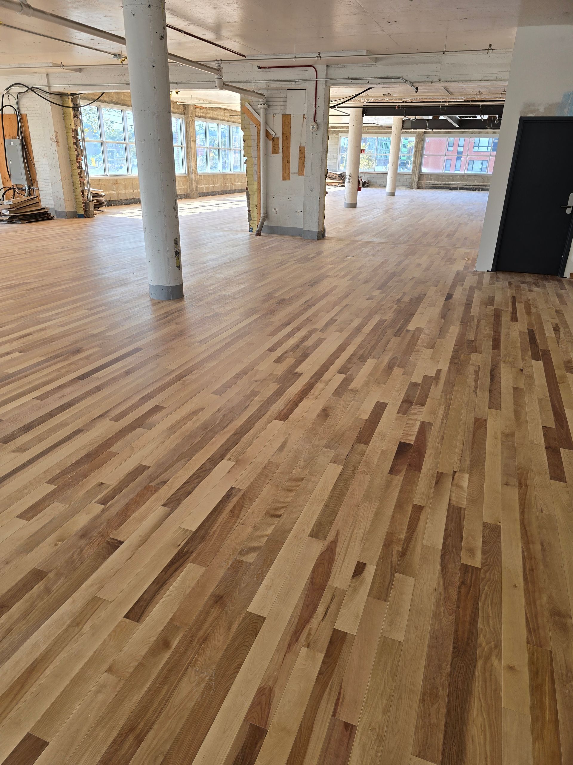 Une grande pièce avec un plancher en bois et des colonnes.