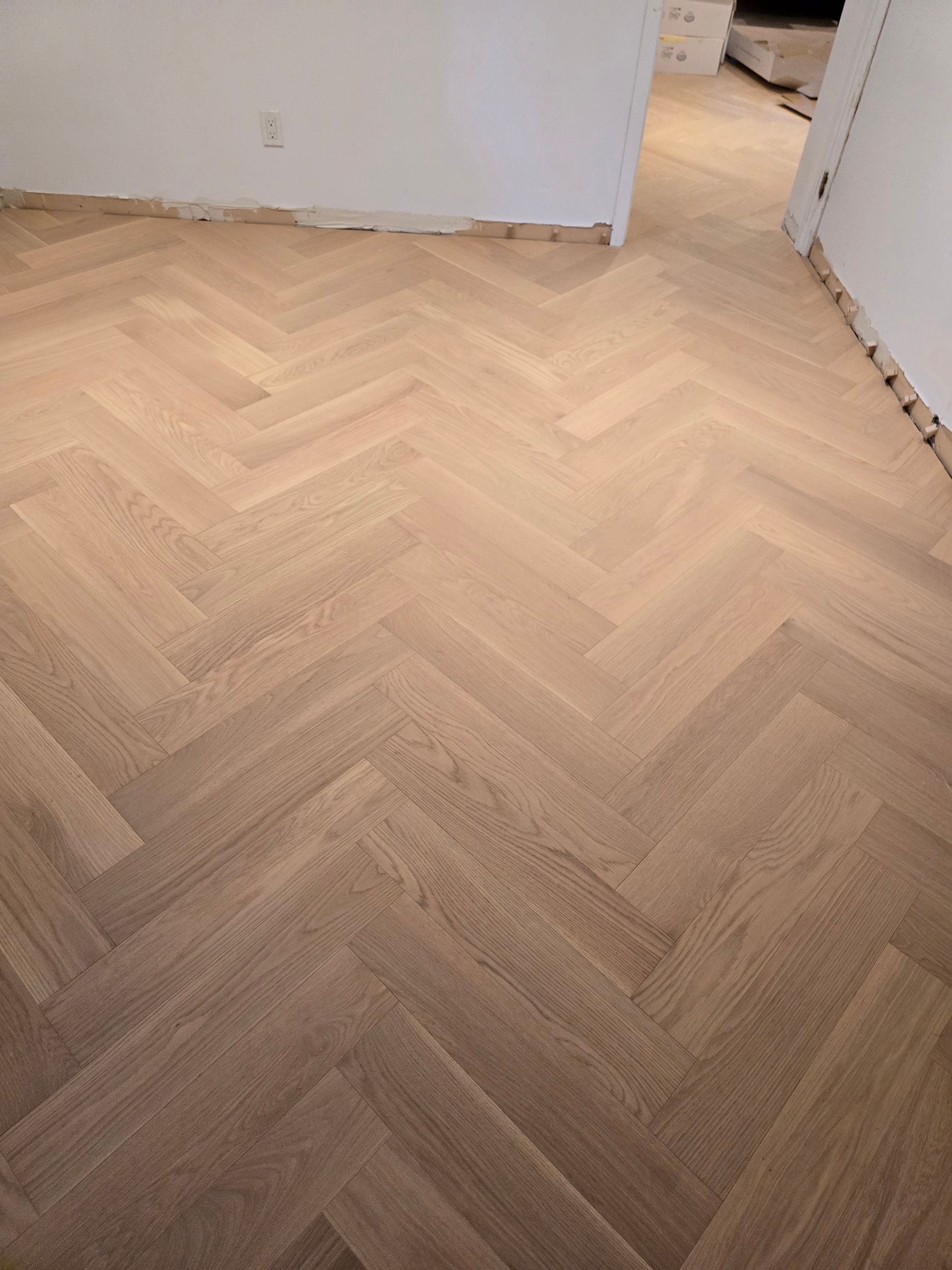 Un plancher en bois avec un motif à chevrons dans une pièce.