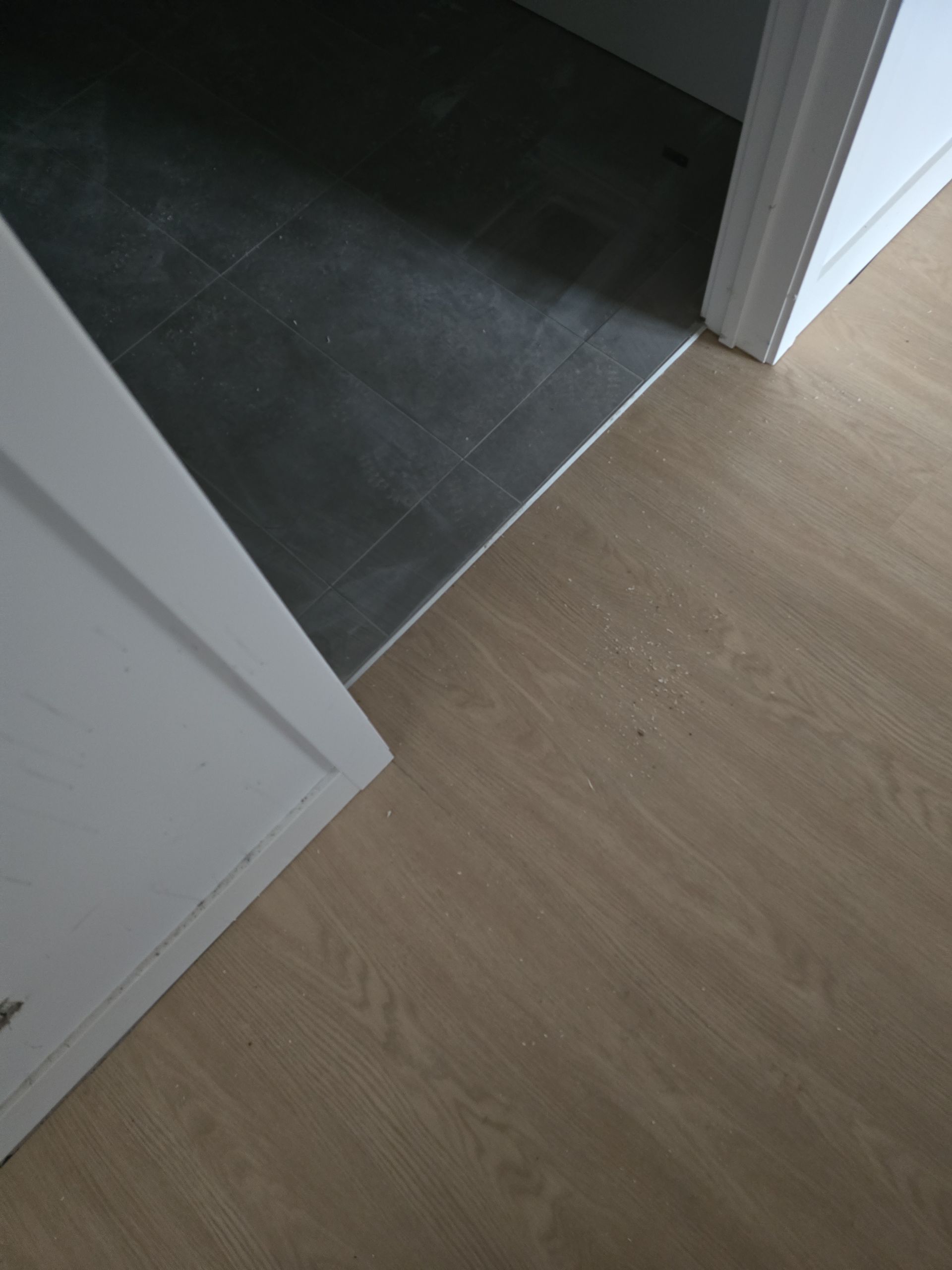 Un gros plan d'un plancher en bois à côté d'une porte dans une pièce.