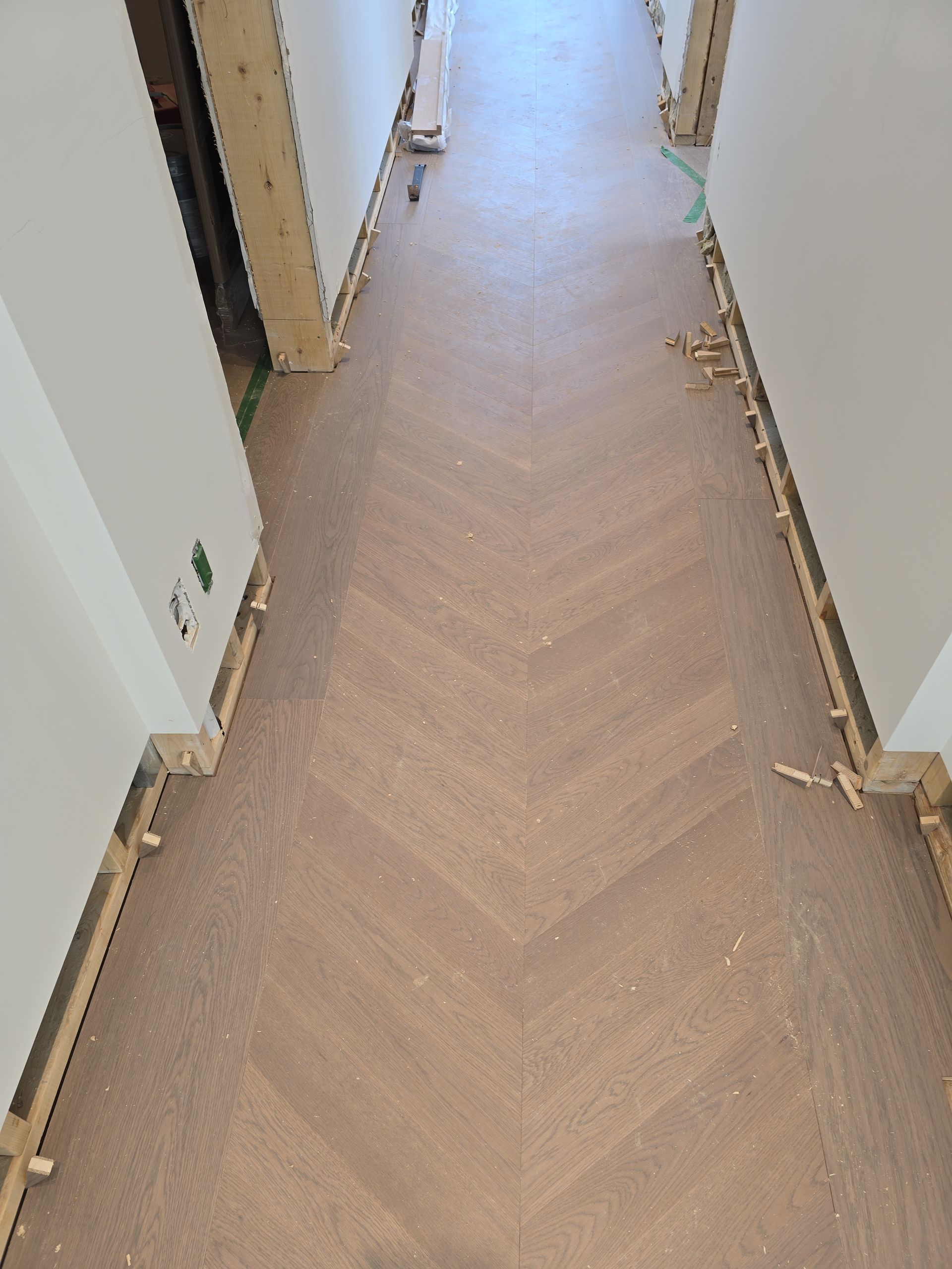 Un couloir avec un plancher en bois et des murs blancs.