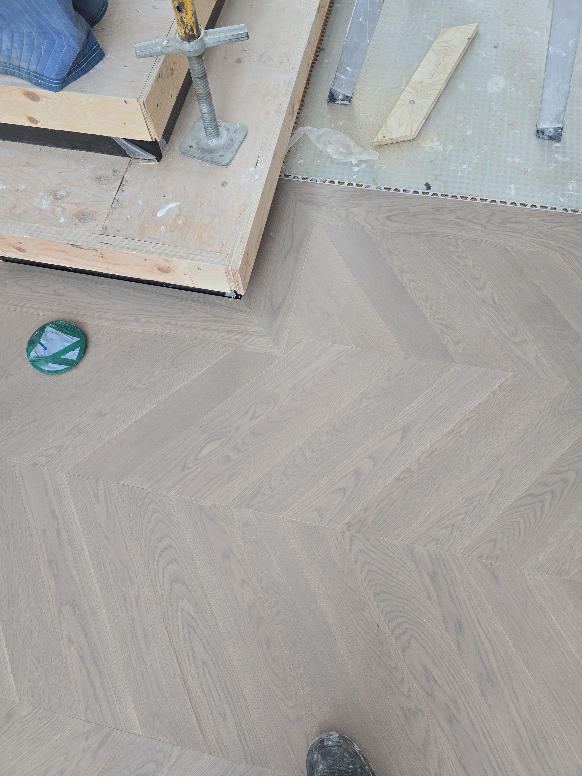 Une personne se tient debout sur un plancher en bois à côté d'un morceau de bois.