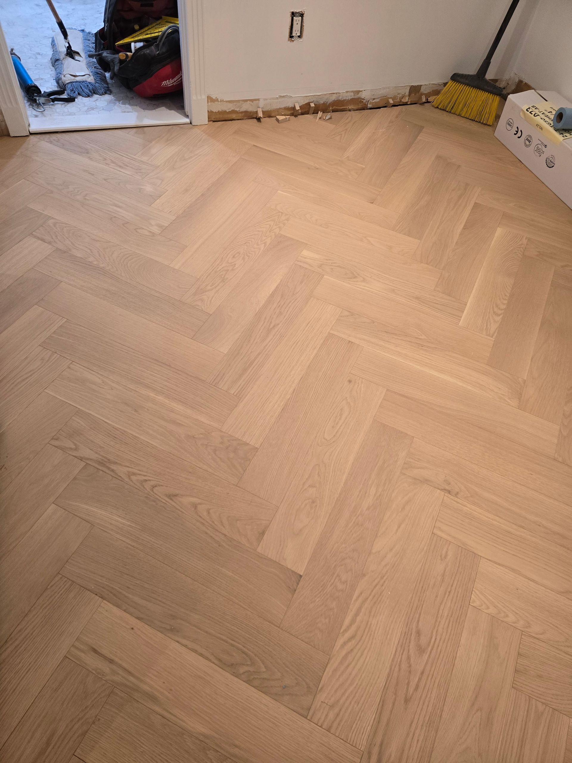 Un parquet à chevrons est en cours d'installation dans une pièce.