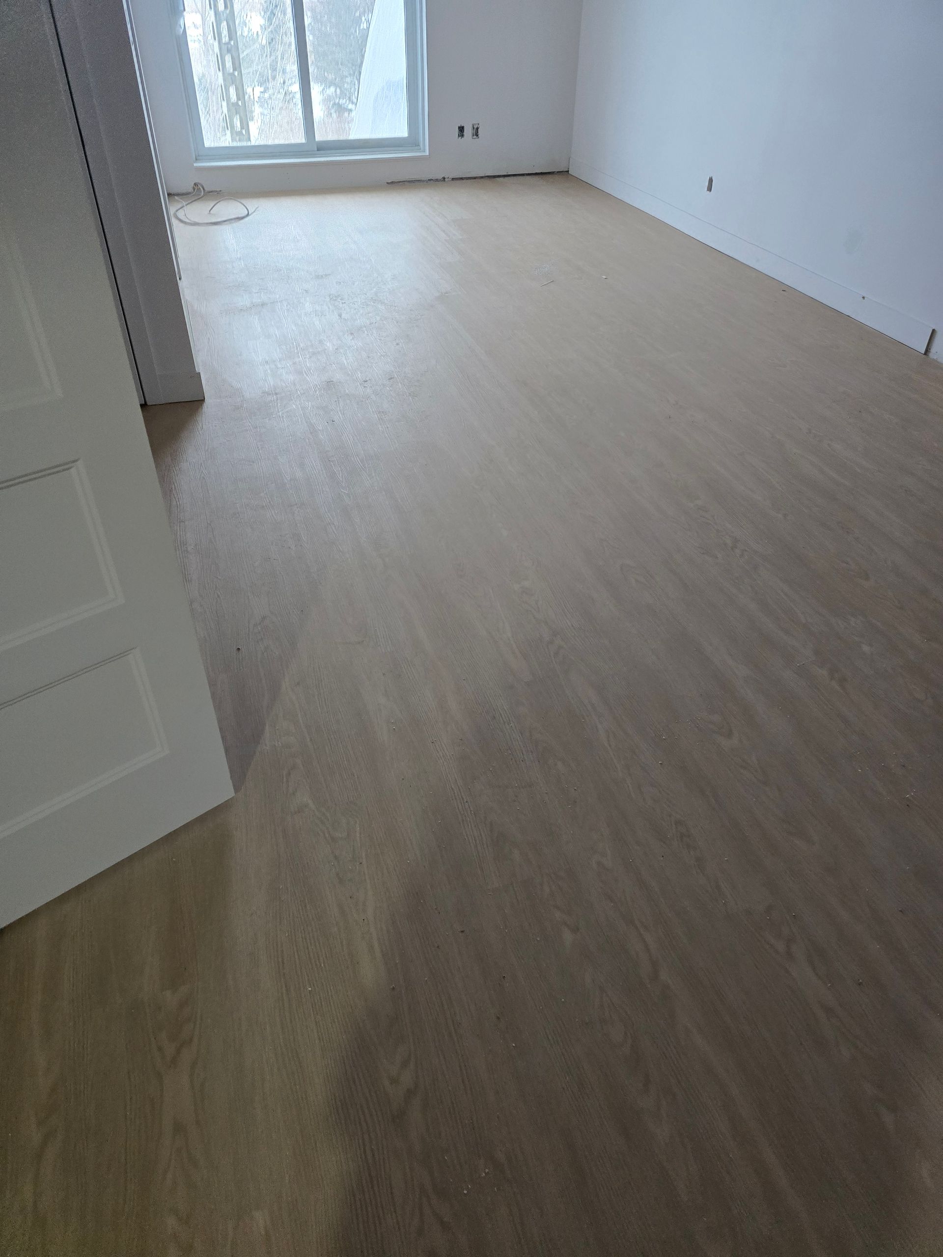 Une pièce avec un plancher en bois et des murs blancs.
