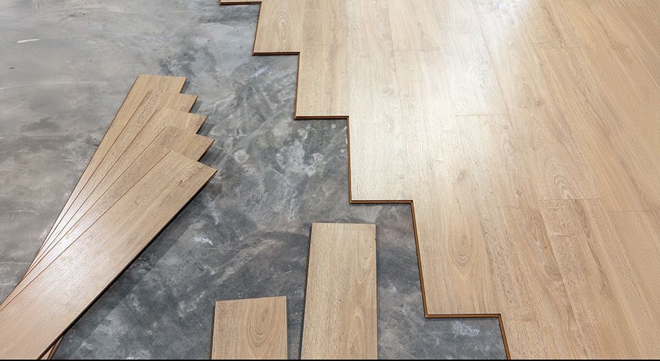 Un plancher en bois est en cours d'installation sur un sol en béton.