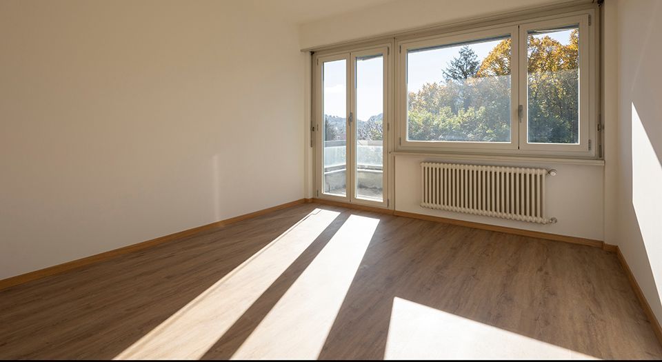 Une pièce vide avec du parquet et une grande fenêtre.