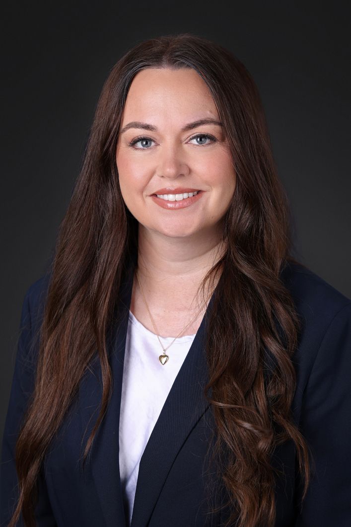 A woman in a blue jacket and white shirt is smiling for the camera.