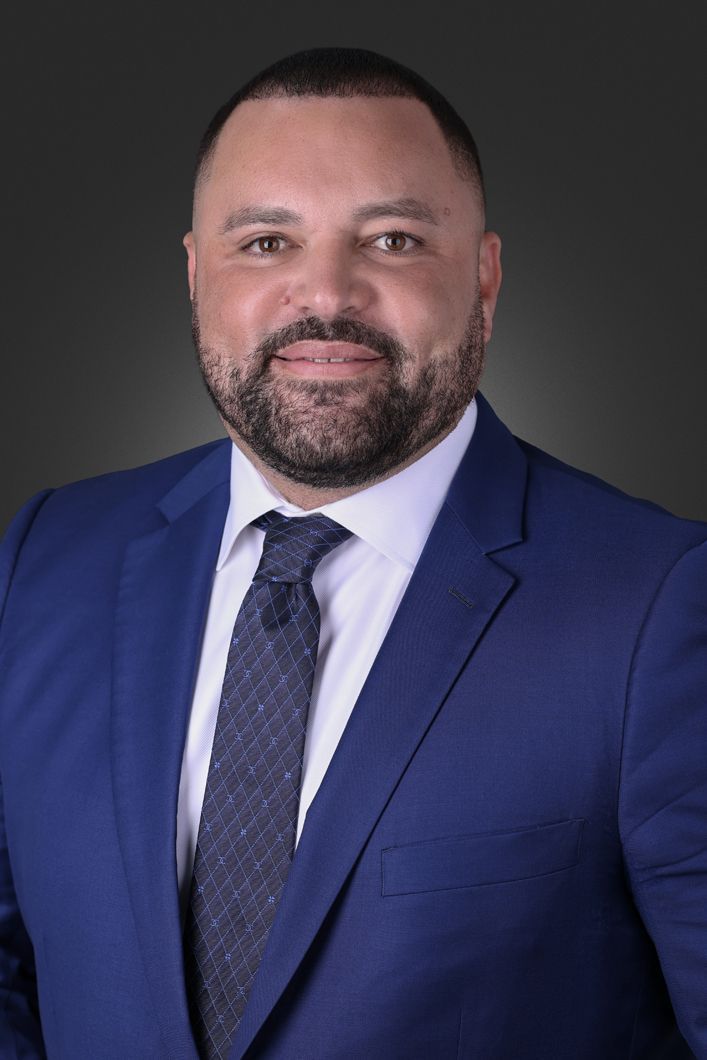 A man with a beard is wearing a blue suit and tie.