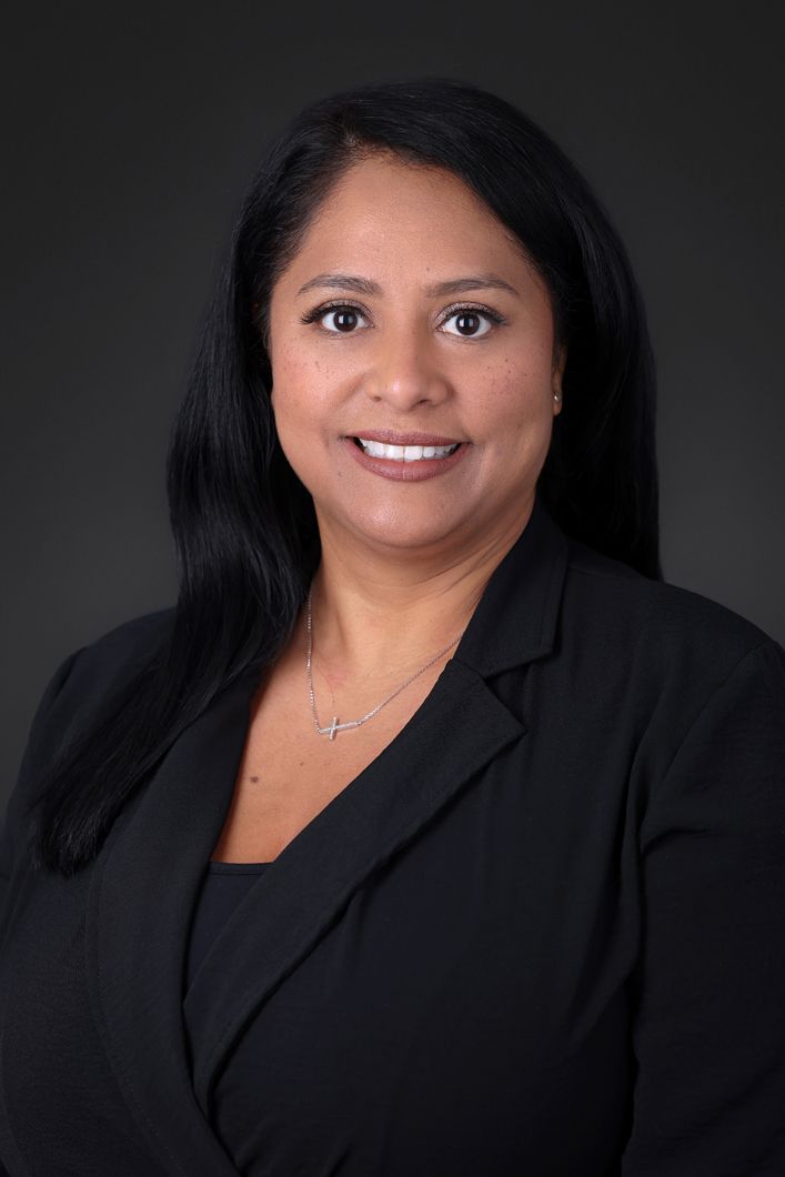 A woman in a black jacket is smiling for the camera