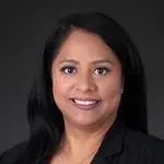 A woman with long black hair is smiling and wearing a black jacket.
