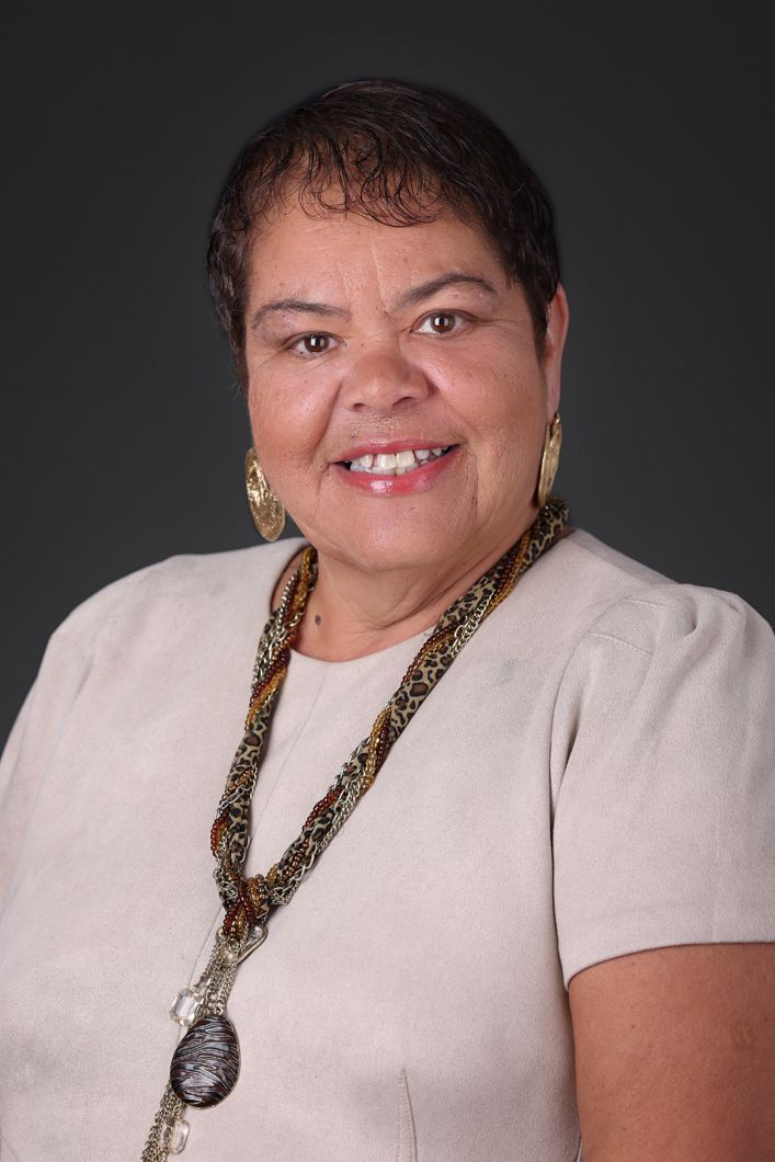 A woman wearing a necklace and earrings is smiling for the camera.