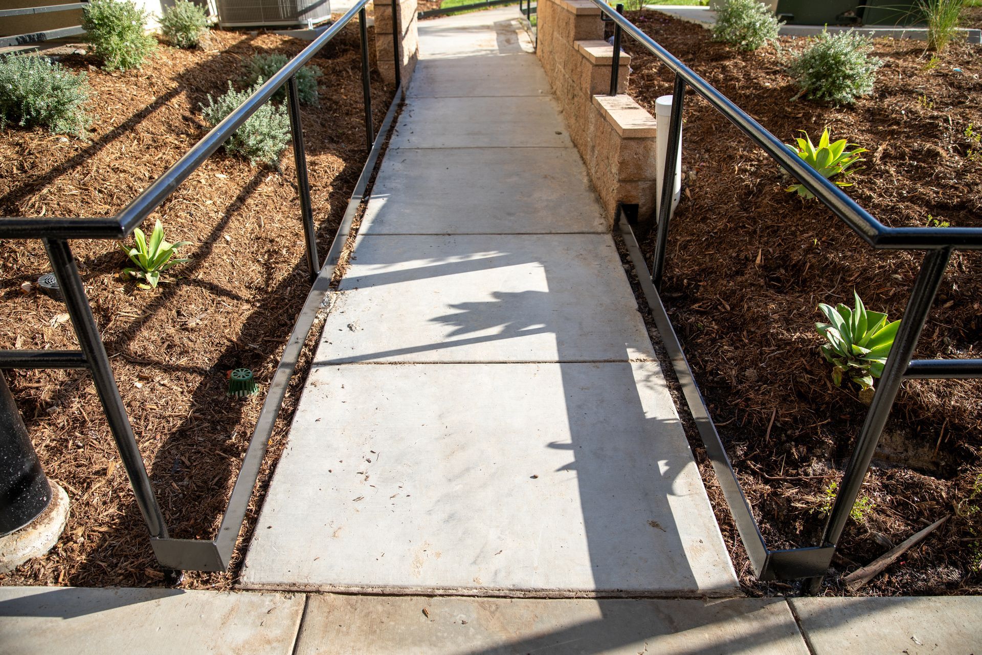 A concrete walkway with a metal railing leading to a building.