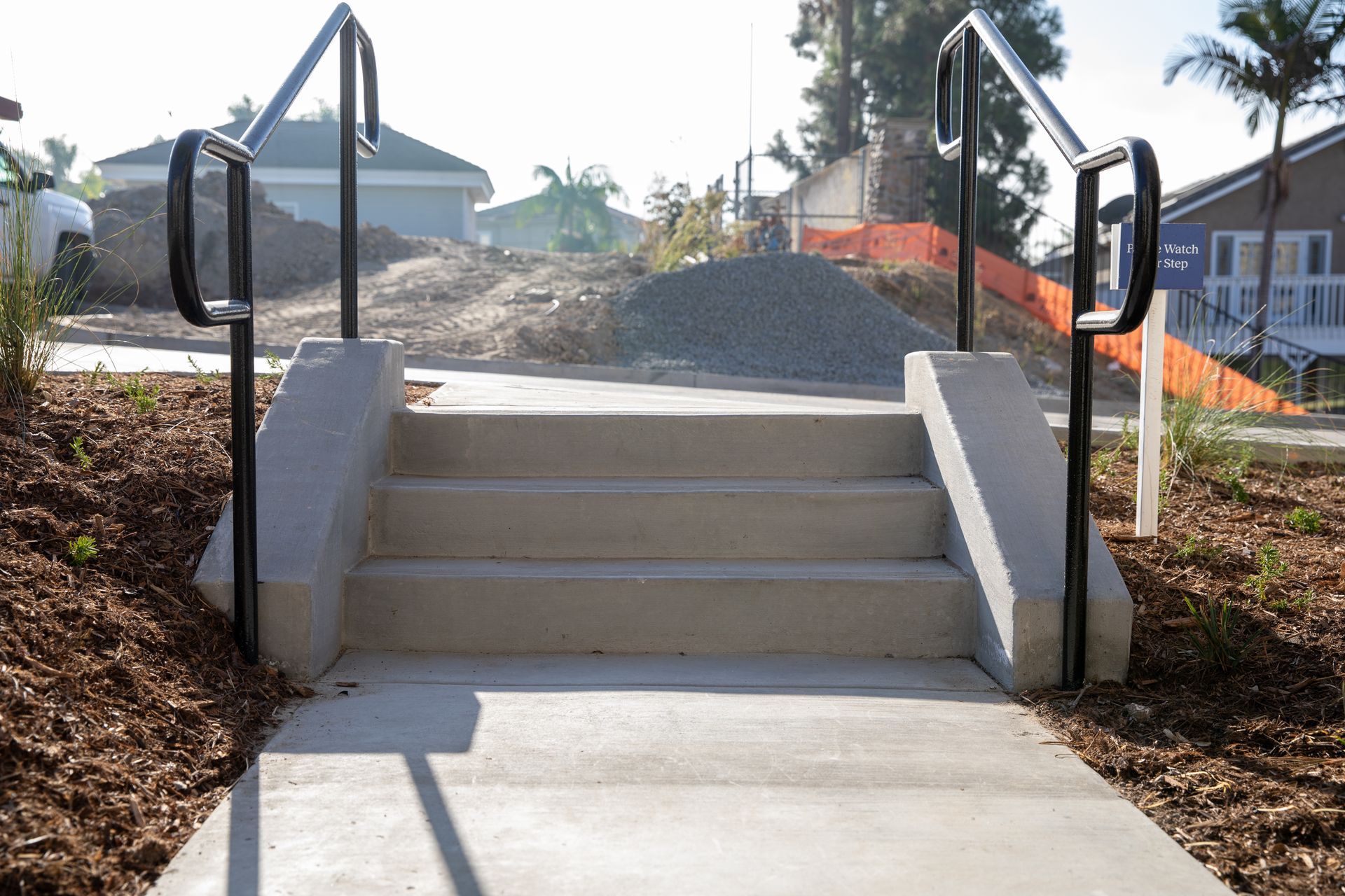 A set of concrete stairs with a black railing