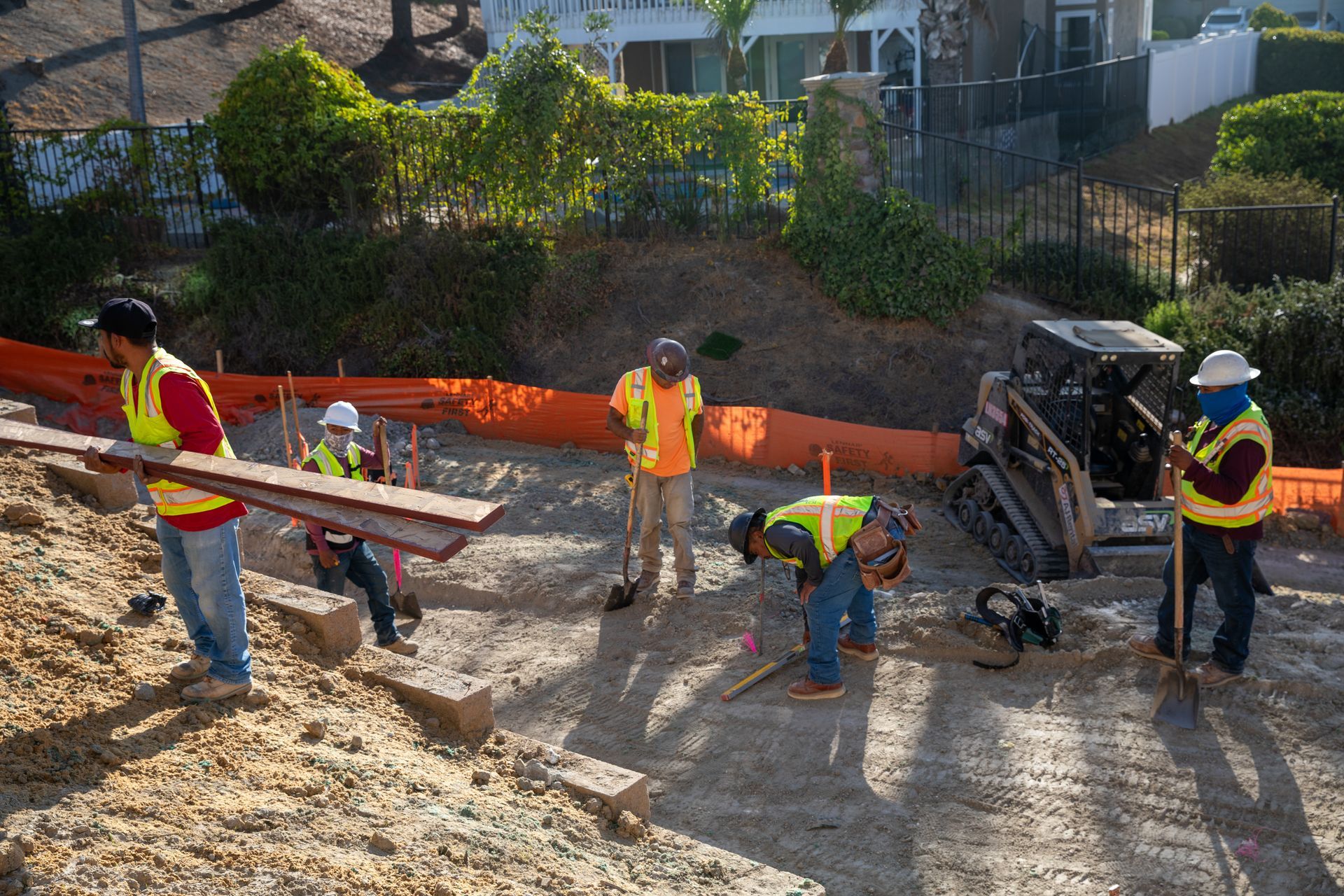 A group of construction workers are working on a dirt road.