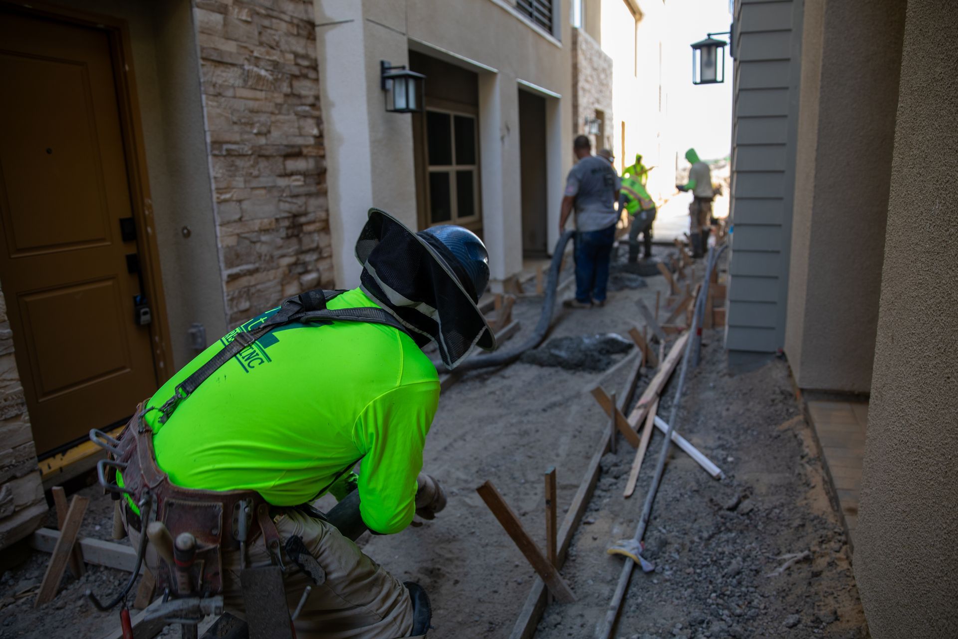 A group of construction workers are working on a sidewalk in front of a building.