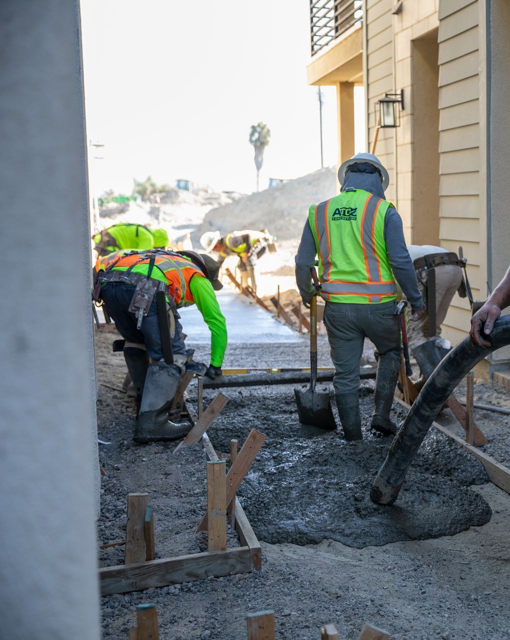 Construction workers pouring and leveling concrete on a paved surface.