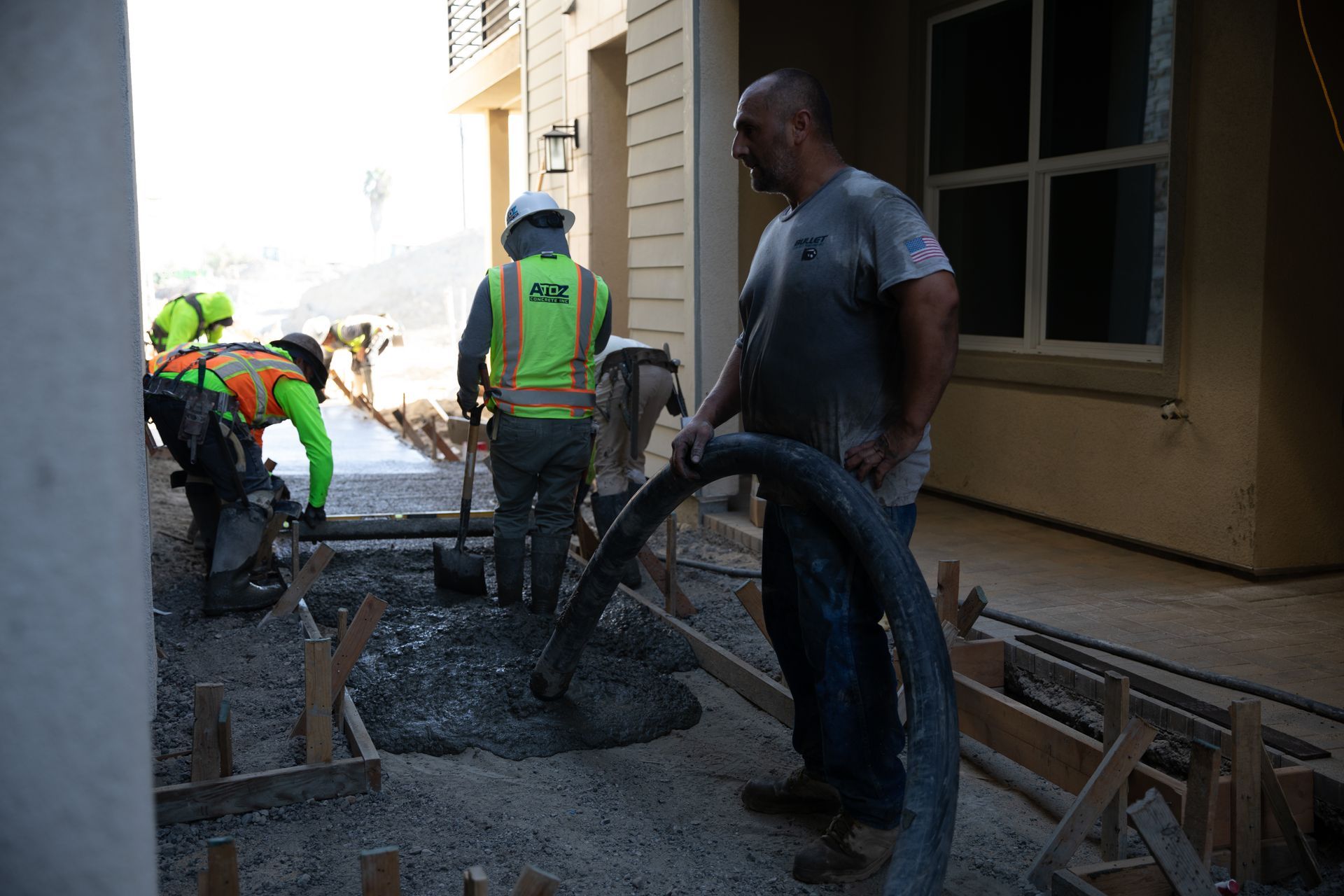 A group of construction workers are working on a sidewalk in front of a building.