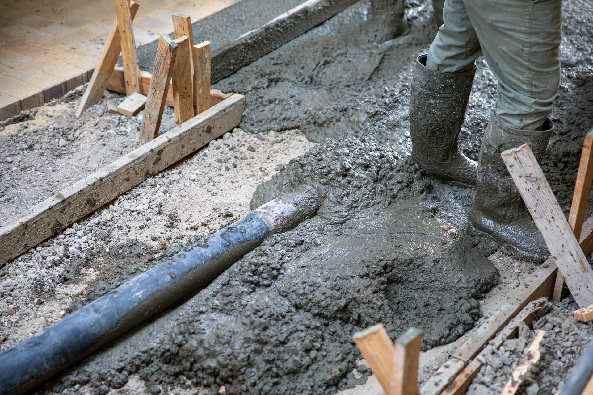 A man is pouring concrete into a hole in the ground.