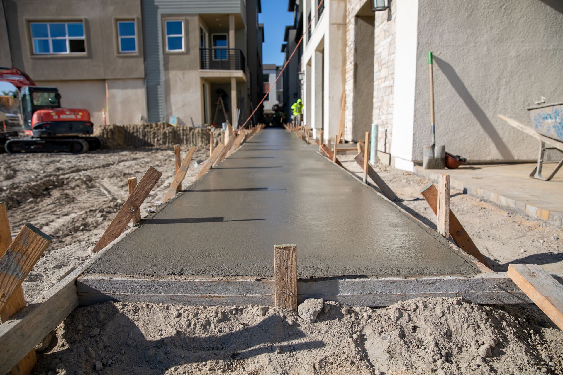Freshly poured concrete walkway at a construction site beside a building under repair