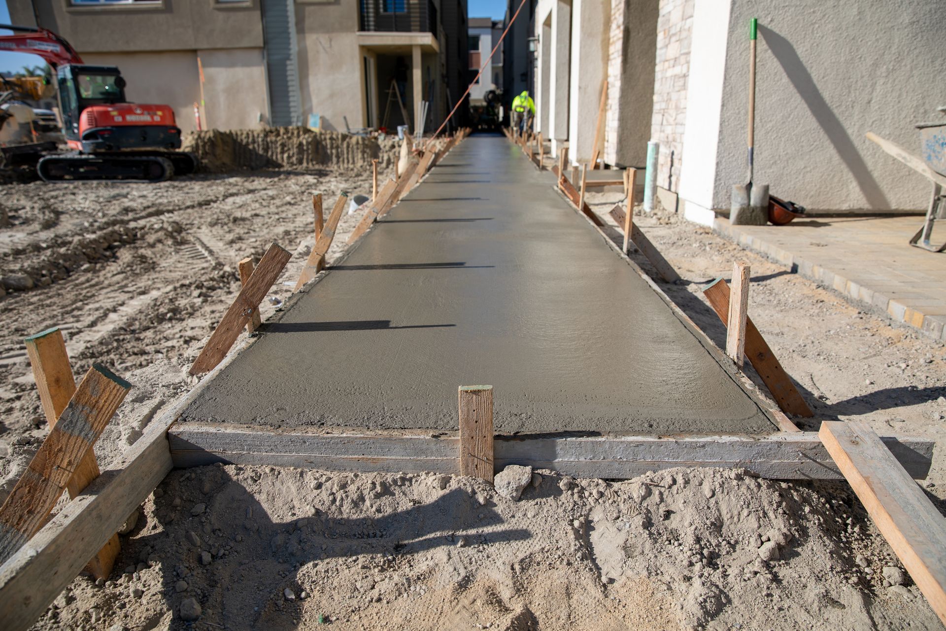 A concrete walkway is being built in front of a house