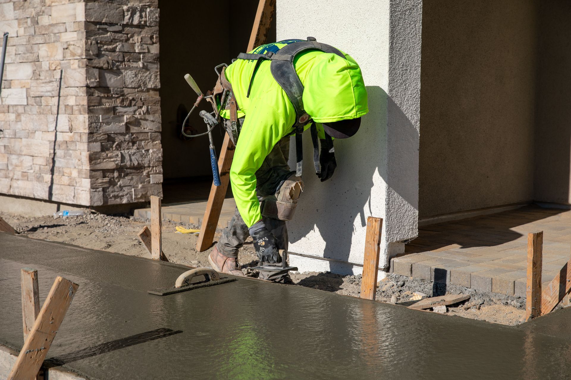 A construction worker is spreading concrete on a sidewalk.