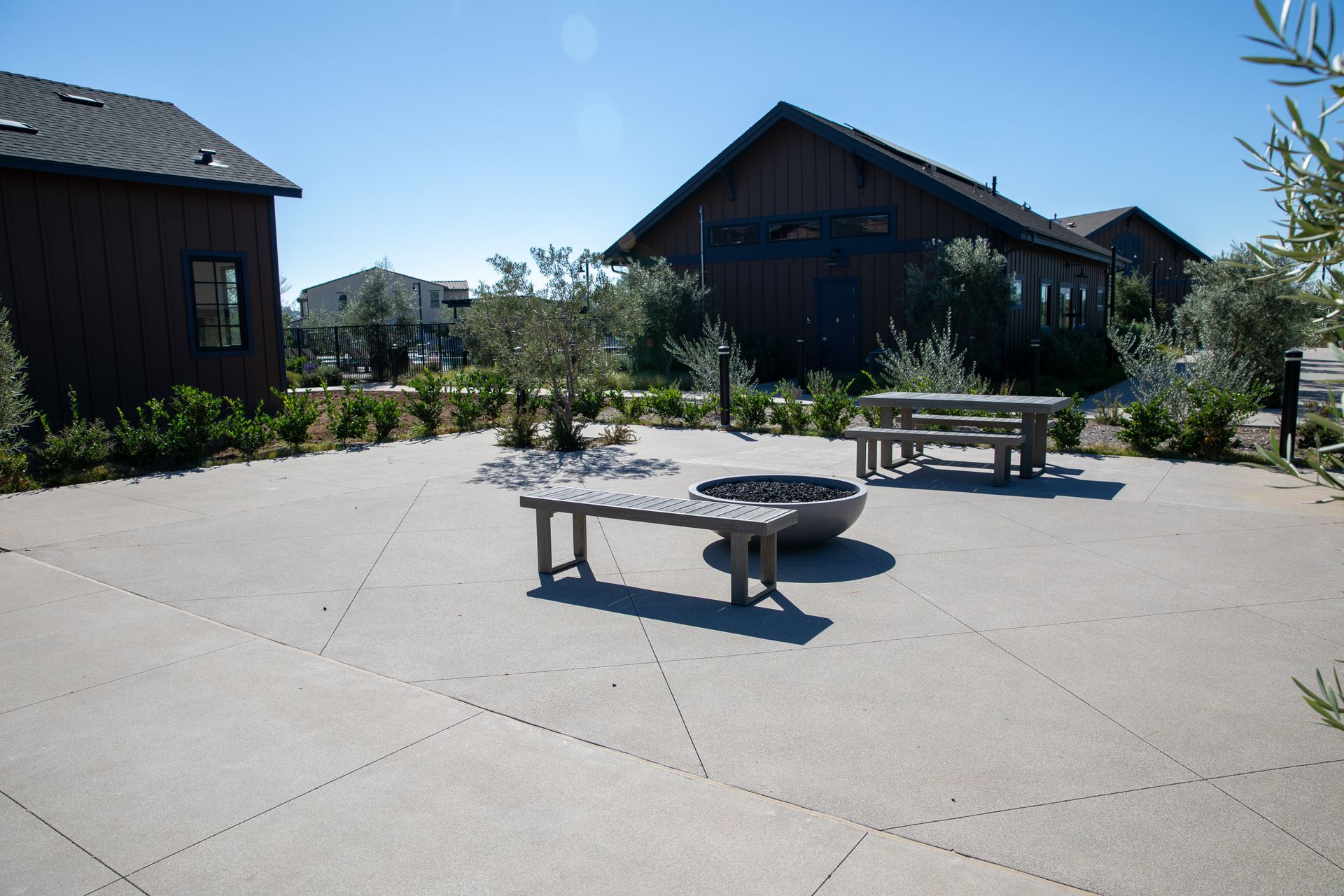A patio with a fire pit and benches in front of a house