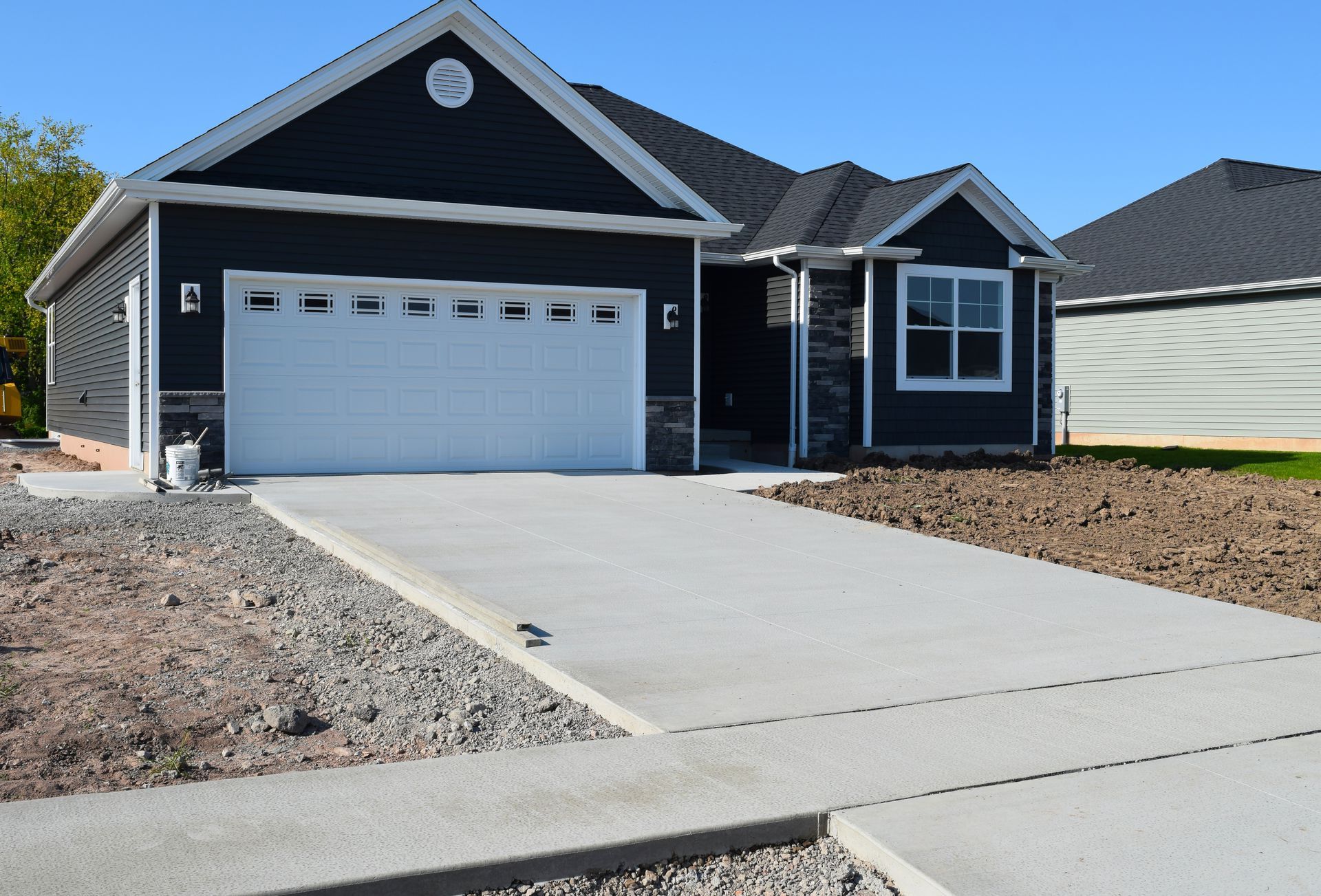 A black house with a white garage door and a concrete driveway