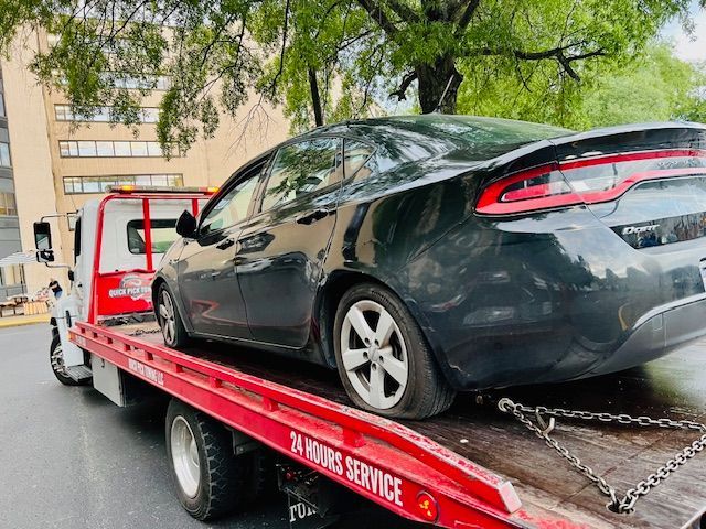 A black car is being towed by a tow truck.