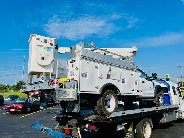 A tow truck with a utility truck on top of it.