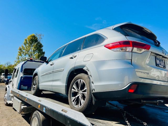 A silver car is sitting on top of a tow truck.