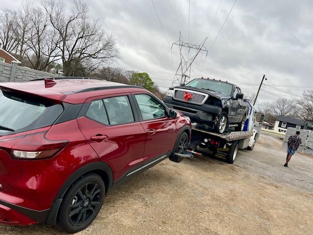 A red car is being towed by a tow truck.