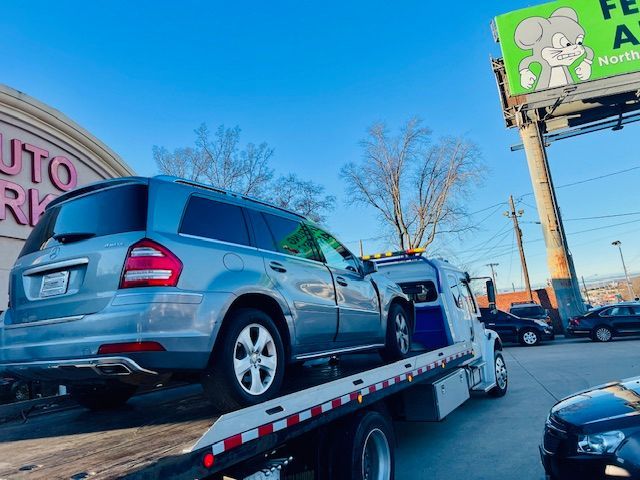 A silver suv is being towed by a tow truck.
