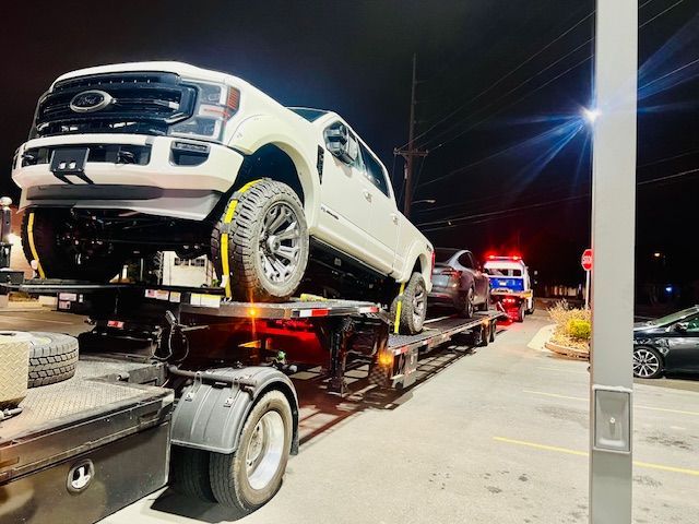 A white truck is sitting on top of a tow truck.