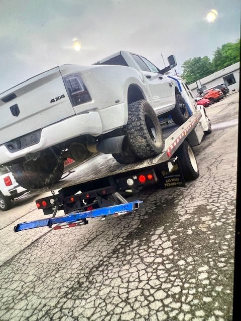 A white truck is being towed by a tow truck