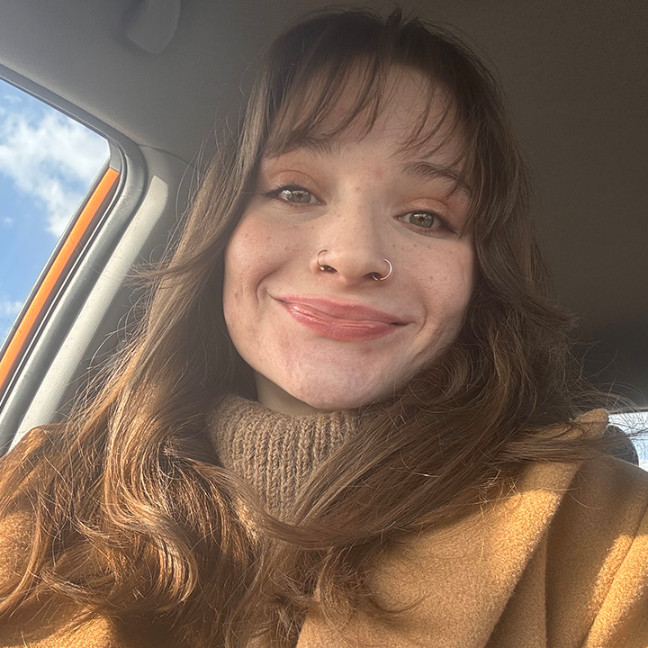 A woman is smiling while sitting in the back seat of a car.