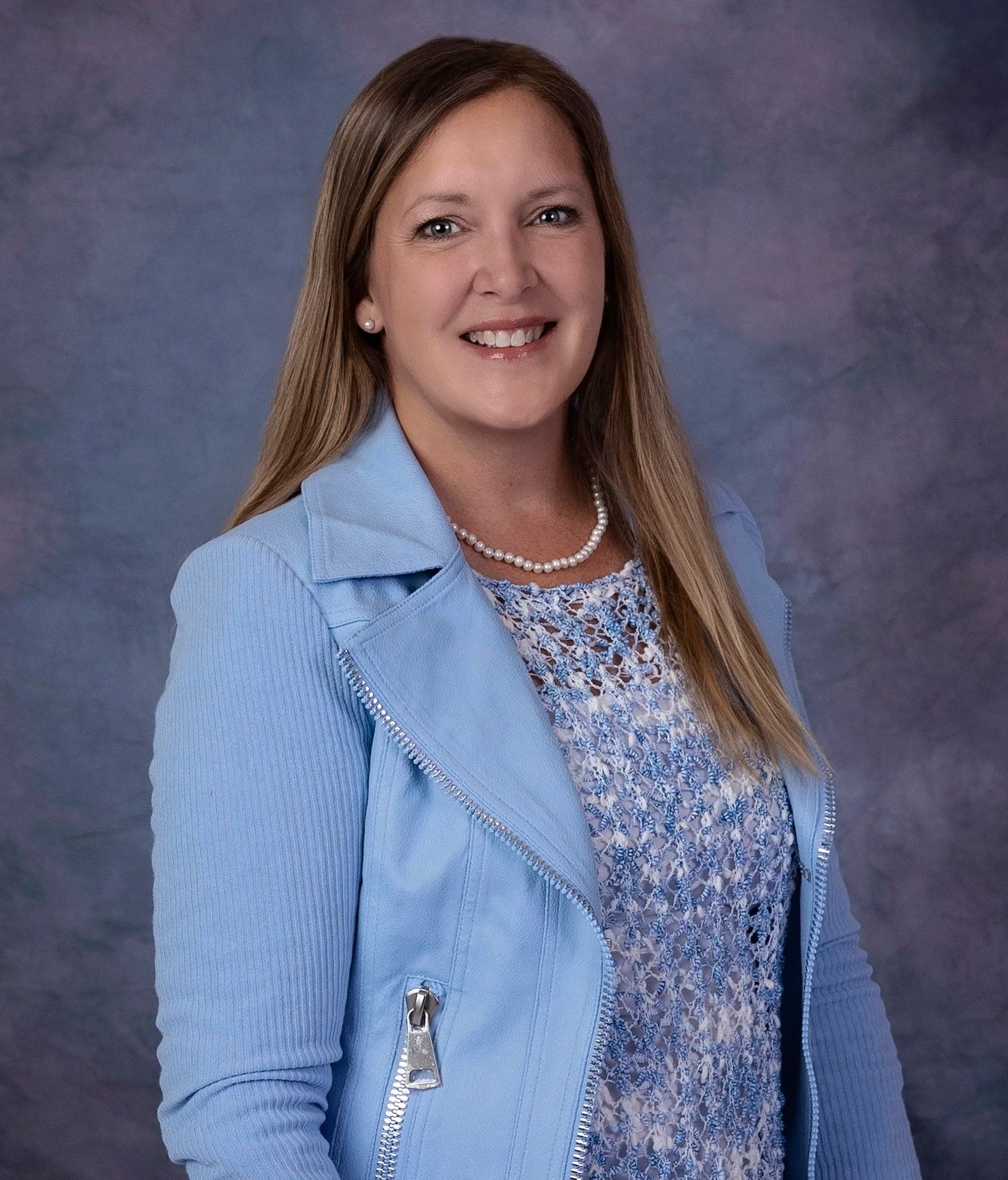 A woman in a purple shirt is smiling for the camera.