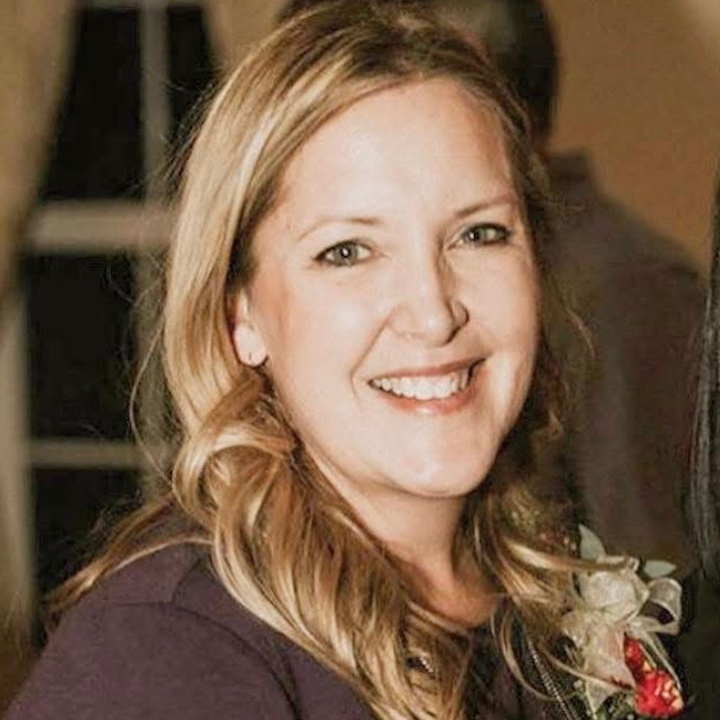 A woman in a purple shirt is smiling for the camera.