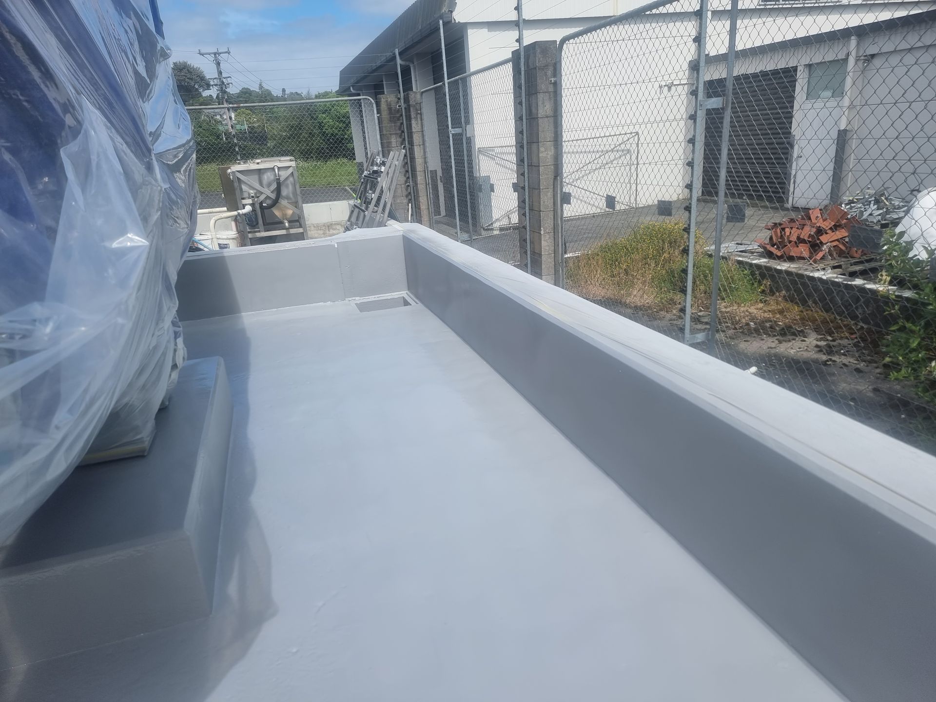 A car is parked on the side of a building next to a fence.